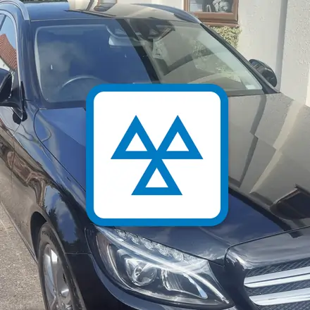 Black car parked in a driveway with an MOT logo overlay