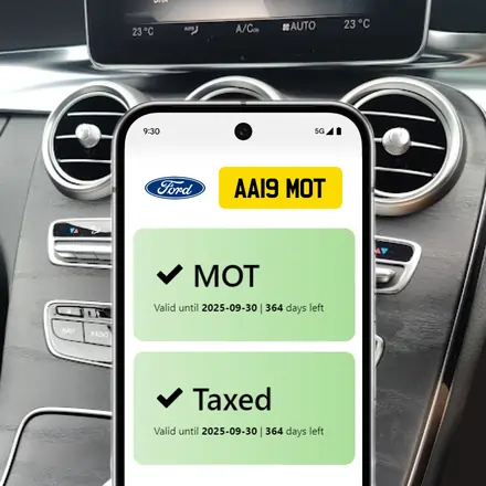 Smartphone displaying MOT and tax status inside a car with dashboard visible